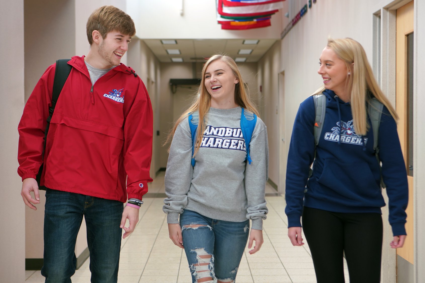 Three Students walking down a hallway talking.