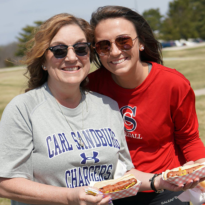 two women holding hot dogs smiling