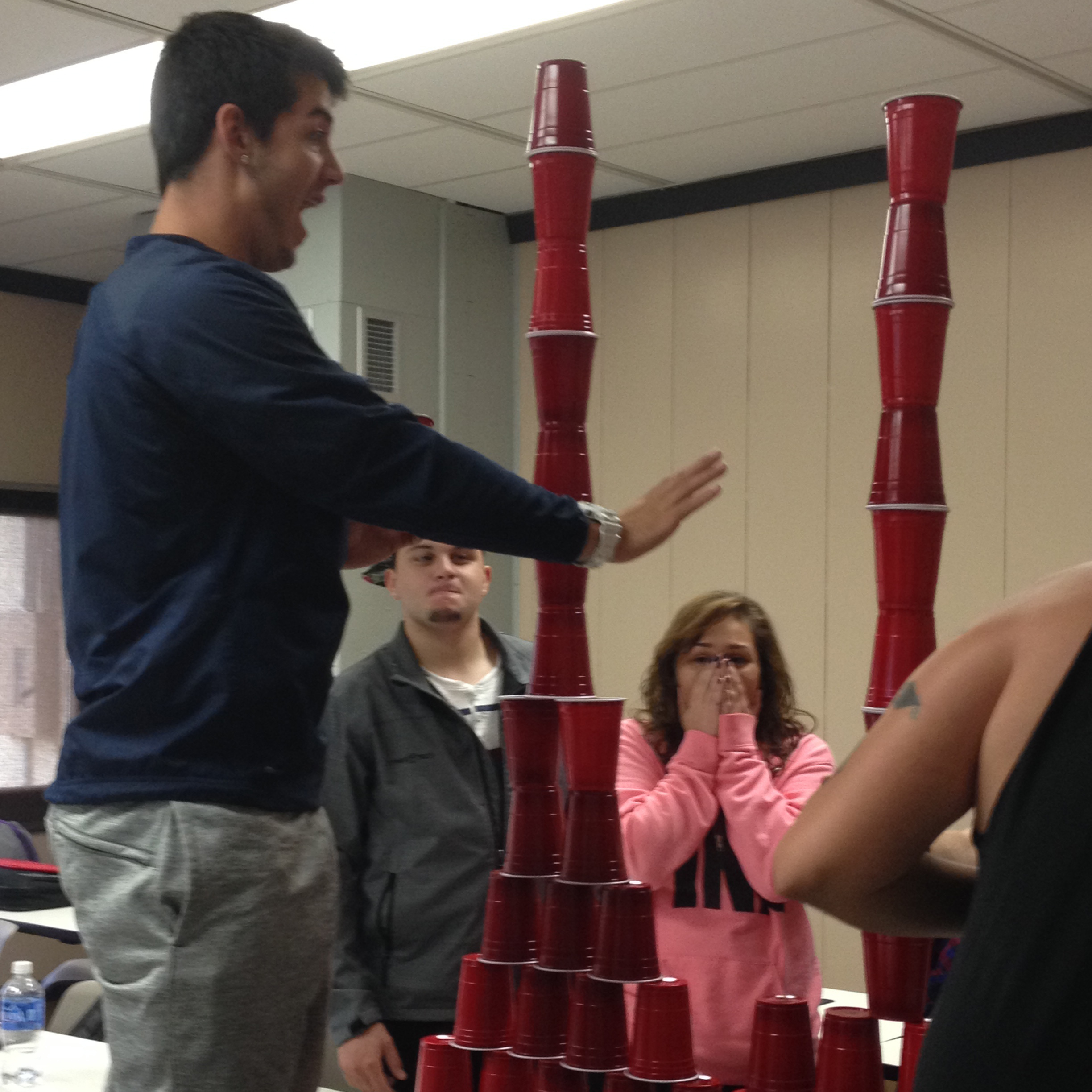 student stacking cups in front a group. 