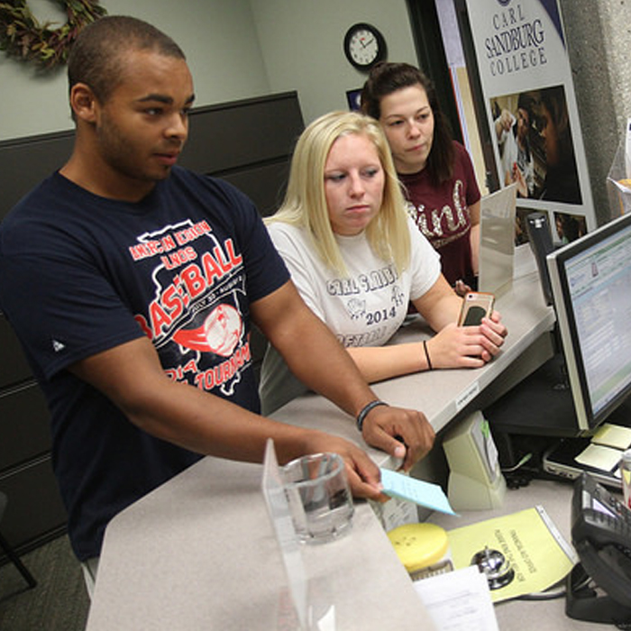 three students standing a the financial aid front desk.