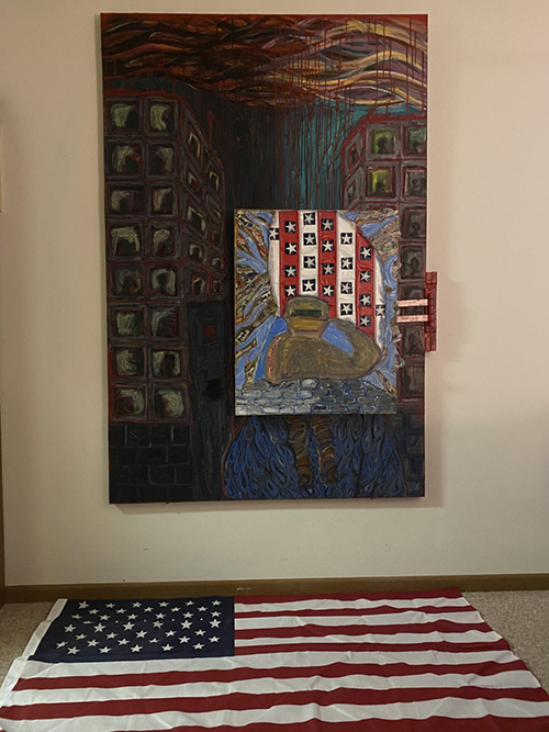 a painting of a city block at night with high rise apartments. On top of that painting is another painting with red and white stripes with blue boxes with white stars in them. Standing in front of the flag a person facing the flag saluting. 