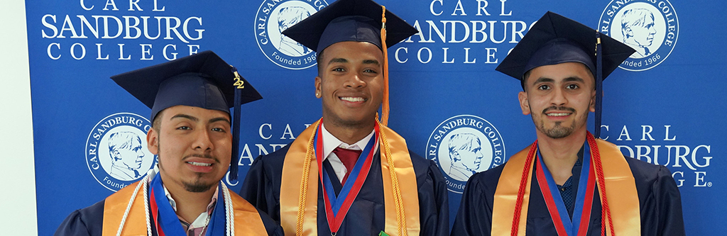 three male students of color with graduation gowns on.