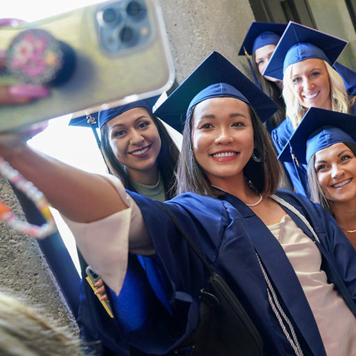 a group of female graduates taking a selfie in the graduation gowns.
