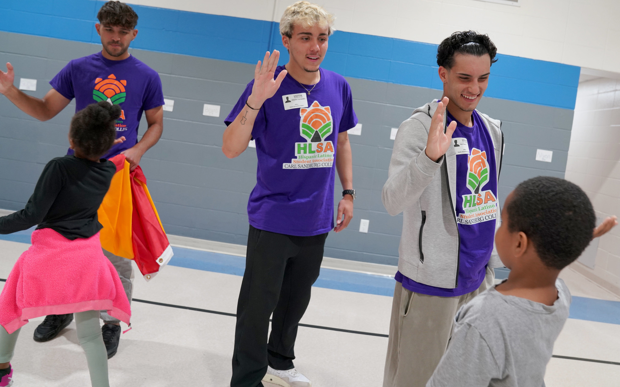 Hispanic Latino Student Association members giving high-fives to Steele Elementary students