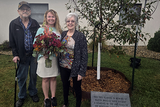 Family standing in front of dedicated tree.