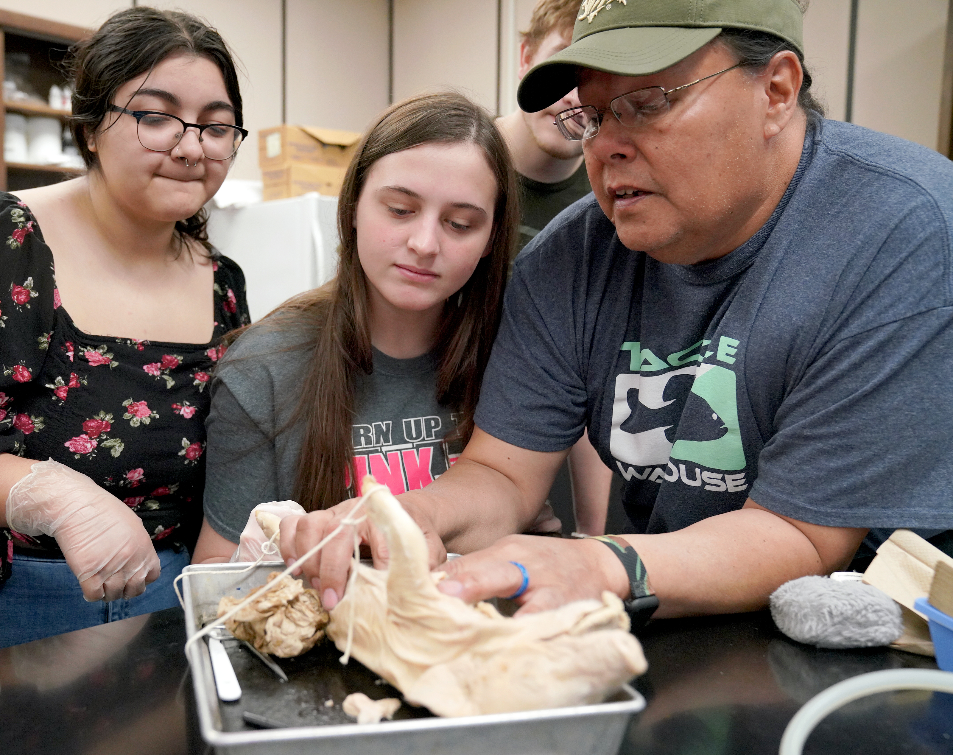Carl Sandburg College student Kathryne Herslow (center) looks on as associate professor of biology Dave Burns assists with dissecting a pig in his anatomy & physiology course.