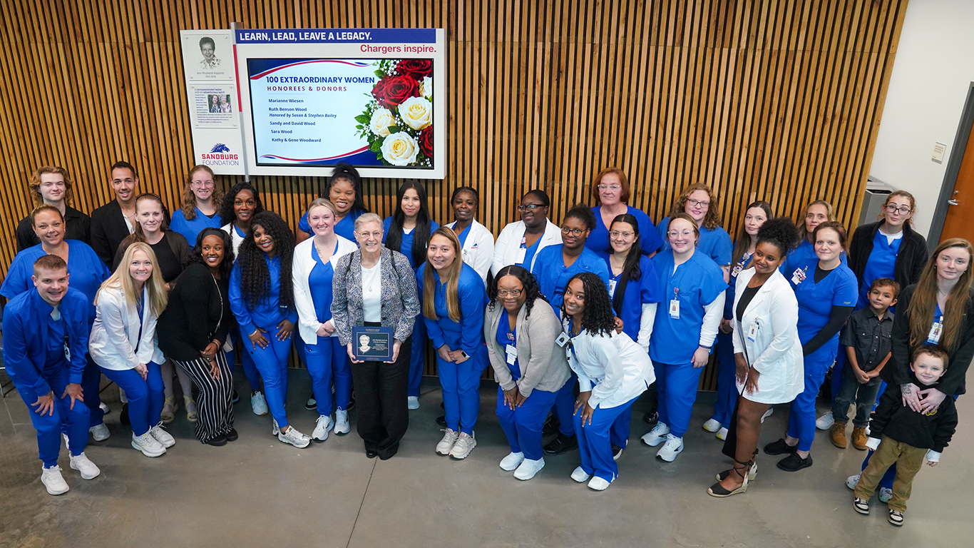 Nursing students in front of Ann Rhykerd-Asplund and 100 Extraordinary Women display