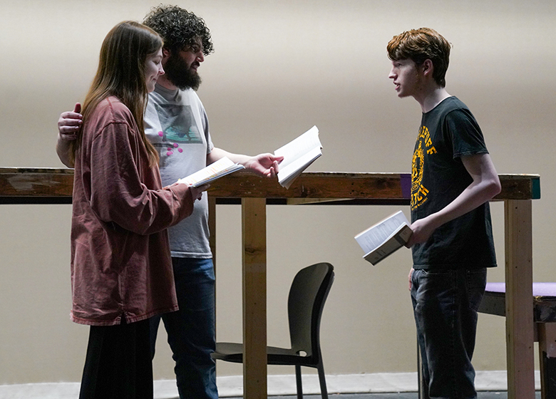Three people reading lines on a stage.