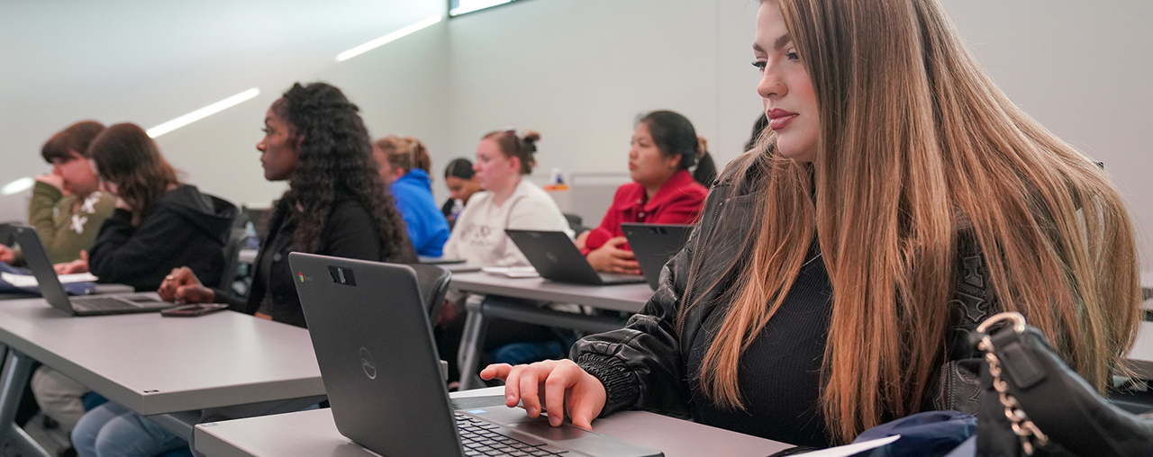 Women looking at laptop in a classroom.