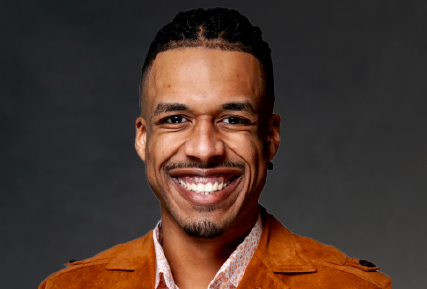 Black man with mustache and goatee smiling.