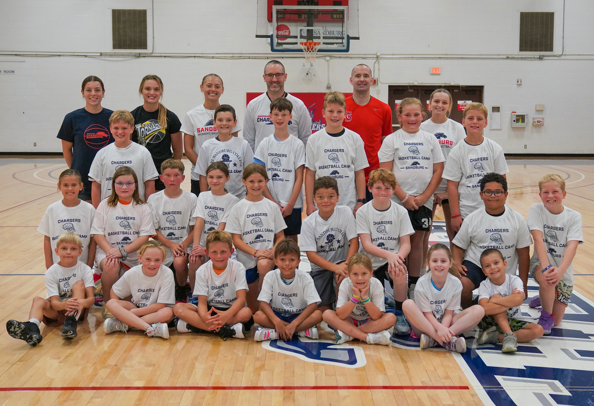 Group photo of basketball camp participants and Chargers coaches and players.
