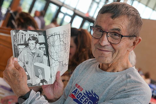 Fred Visel holding time capsule item that includes a picture of him.