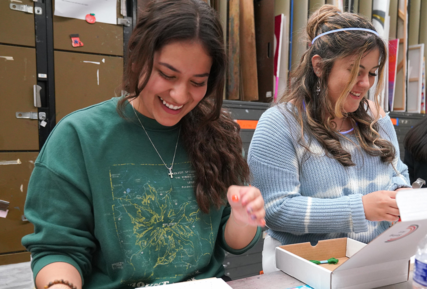 two students in art class drawing.