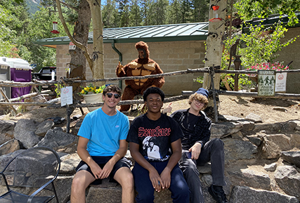 Students sitting on rocks in front of a Yeti statue.