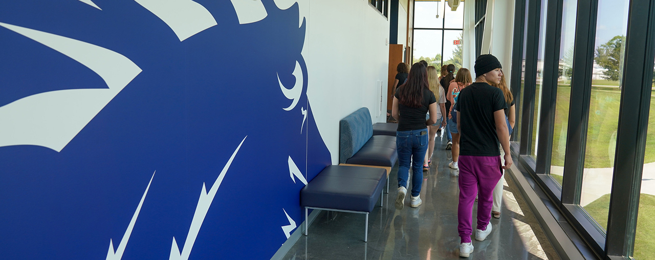 Students in a hallway with a stylized images of a horse head on the wall.