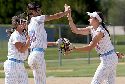 three softball players celebrating after a great play.