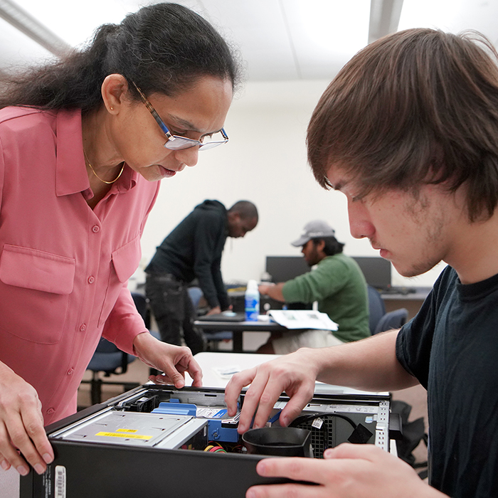 Instructor and student looking at the inside of a computer.