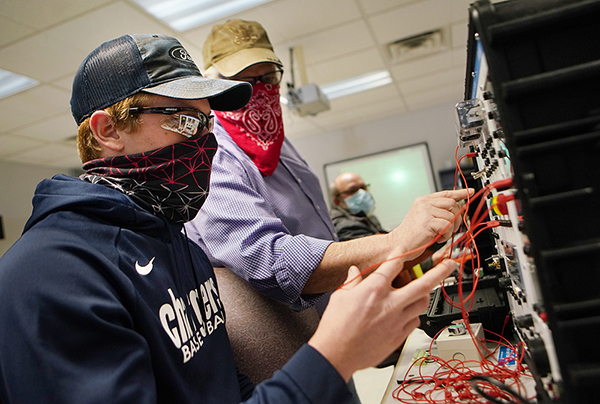 Image of Sam Scott and instructor working on electrical simulator during lab.
